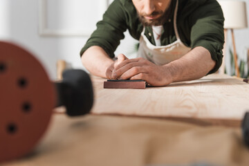 Wall Mural - Cropped view of blurred restorer sanding wood in workshop.