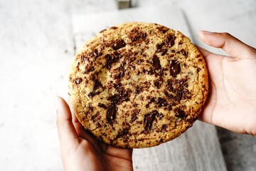 Sticker - Little hand holding single giant chocolate chip cookie, selective focus