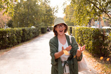 Happy Smiling Senior Asian Woman On Walk In City Park Glad To Autumn Coming