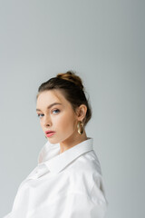 Wall Mural - portrait of young woman with natural makeup posing in white shirt isolated on grey.