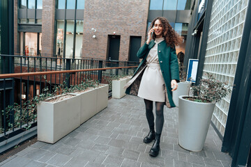 Young woman talking on mobile phone while walking in the city