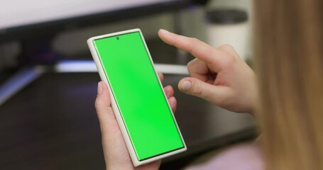 Woman using smartphone in vertical mode with green mock-up screen