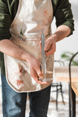 Wall Mural - Cropped view of restorer in apron holding calipers in workshop.