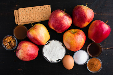 Wall Mural - Cheesecake Stuffed Apple Ingredients on a Wooden Table: Gala apples, cream cheese, and other ingredients on a dark wood background