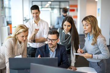 Large group of successful business people working together and discussing project at computer on a meeting in modern office.