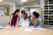 © wavebreak3 - Diverse female and male businesspeople at desk talking and working in office