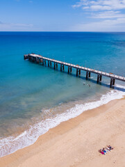 Porto Santo old pier. Aerial view on a sunny summer day with people relaxing on the beach and sunbathing.