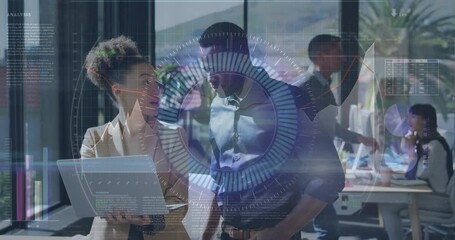 Canvas Print - Animation of data processing over diverse man and woman discussing over a laptop at office