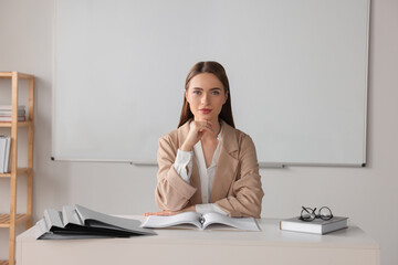 Wall Mural - Young teacher sitting at table in classroom