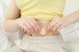 Fototapeta  - Woman applying contraceptive patch onto her belly on bed, closeup
