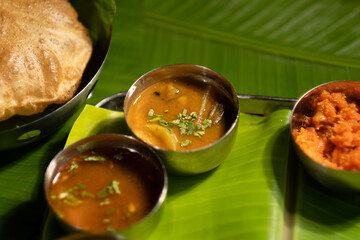 A closeup view of sauces and flatbread served on a traditional south Indian meal plate.