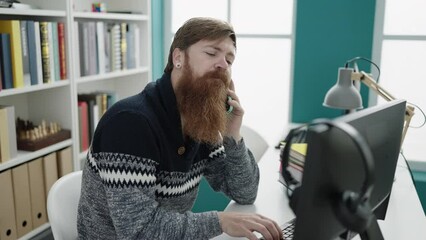 Canvas Print - Young redhead man student using computer talking on smartphone at library university