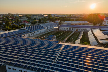 Wall Mural - Aerial view of solar power plant with blue photovoltaic panels mounted on industrial building roof for producing green ecological electricity at sunset. Production of sustainable energy concept