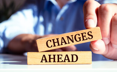 Poster - Closeup on businessman holding a wooden block with CHANGES AHEAD message, business concept