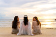 © CandyRetriever  - Group of Young Asian woman friends sitting and talking together on tropical island beach at summer sunset. Attractive girl enjoy and fun outdoor lifestyle travel on beach holiday vacation at the sea