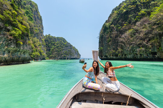 asian woman friend using mobile phone taking selfie together during travel on boat passing island be