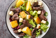 Delicious French Salad With Gizzards, Potatoes, Lettuce, Onions And Croutons Close-up In A Plate On The Table. Horizontal Top View From Above