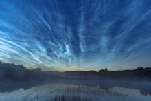 Blue Silvery Clouds Or Noctilucent Clouds Or Night Shining Clouds Over Water And Fog. Noctilucent Clouds Above The River.