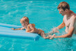 © Cavan Images - Dad and baby daughter swim on an inflatable mattress in the outd