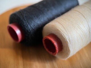 Selective focus view of cotton thread on spool for sewing material with wood background. Macro photography.