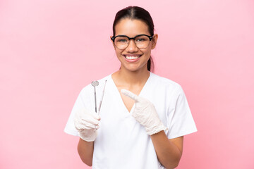 Wall Mural - Dentist Colombian woman isolated on pink background pointing to the side to present a product