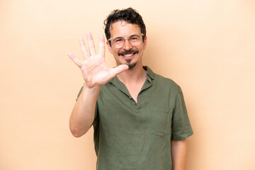 Wall Mural - Young caucasian man isolated on beige background counting five with fingers