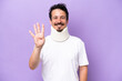 © luismolinero - Young caucasian man wearing neck brace isolated on purple background happy and counting four with fingers