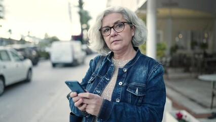 Poster - Middle age woman with grey hair using smartphone at street