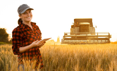 Sticker - Woman farmer with digital tablet on a background of harvester. Smart farming concept.	