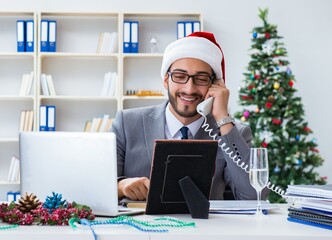 Wall Mural - Young businessman celebrating christmas in the office