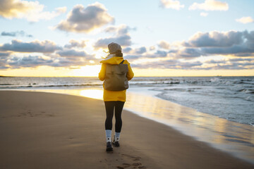 Happy tourist in a yellow jacket standing and looking on sea. Lifestyle, travel, tourism, nature, active life.