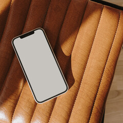 flatlay mobile phone on leather bench or chair with elegant soft sunlight shadows. flat lay, top vie