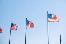 American Flags Blowing In The Wind Against Bright Blue Sky