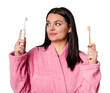 A woman in a pink bathrobe holds both an electric toothbrush and a traditional toothbrush, with a look of uncertainty as she compares the two.