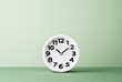 Plain wall clock on pastel green background desk. Ten o'clock. copy space, time management or business concept. Opening or closing hours. Schedule or working hours. daylight saving time