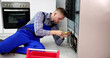 Cropped Image Of Serviceman Working On Fridge With Screwdriver