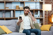 © Liubomir - Sad and depressed man alone at home sitting on sofa, freelancer in casual clothes holding smartphone, unsatisfiedly reading bad news online from phone.
