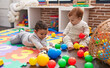 © Krakenimages.com - Two adorable babies playing with balls sitting on floor at kindergarten