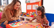 © Krakenimages.com - Teacher and toddler playing with maths puzzle game sitting on table at kindergarten