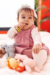 Wall Mural - Adorable hispanic baby bitting maraca sitting on bed at bedroom