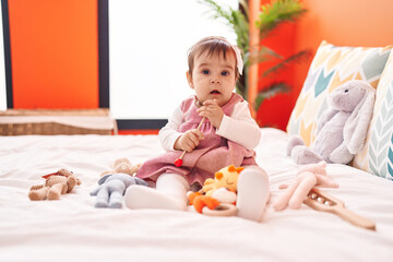 Sticker - Adorable hispanic baby playing maraca sitting on bed at bedroom