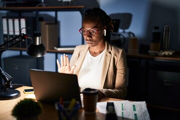 Sticker - Beautiful black woman working at the office at night doing stop sing with palm of the hand. warning expression with negative and serious gesture on the face.