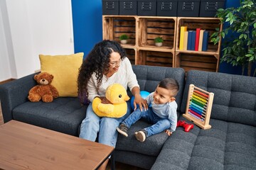Canvas Print - Mother and son playing with toys sitting on sofa at home