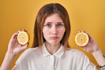 Wall Mural - Beautiful woman holding lemons depressed and worry for distress, crying angry and afraid. sad expression.