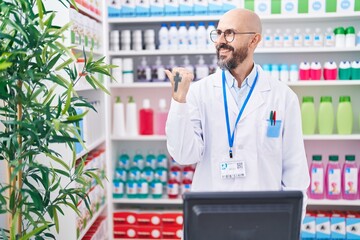 Sticker - Hispanic man with tattoos working at pharmacy drugstore pointing thumb up to the side smiling happy with open mouth