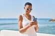 © Krakenimages.com - African american woman smiling confident using smartphone at seaside