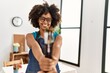Young african american woman smiling confident holding paintbrushes at art studio