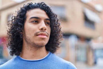 Sticker - Young latin man looking to the side with serious expression at street