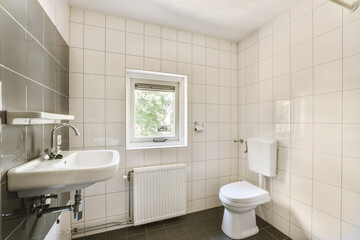 Wall Mural - a bathroom with white tiles on the walls and black tile flooring around the tub, sink, and toilet