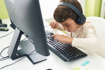 Poster - Adorable hispanic boy student using computer sitting on table at classroom